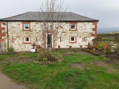 a brick house with a tree in front of it at Cottage at Inch Farm solitude beside the River in Longtown