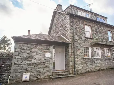 an old stone house with a white door at Plumblands in Ambleside