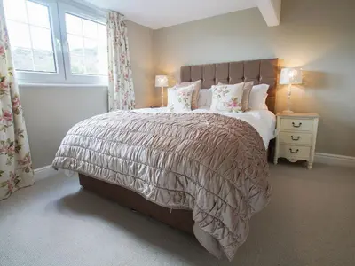 a bedroom with a large bed and two windows at Plumblands in Ambleside