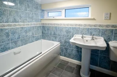 a blue tiled bathroom with a sink and a bath tub at Langdale Hideaway in Chapel Stile