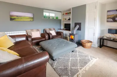 a living room with a leather couch and a fire place at Langdale Retreat in Chapel Stile