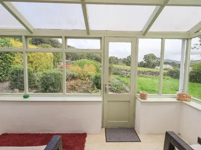 a conservatory with a door and a view of a garden at Blease Garth in Threlkeld