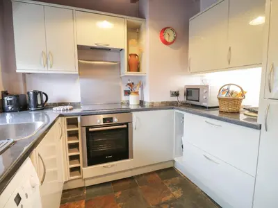 a kitchen with white cabinets and a stove top oven at Beckside Cottage in Welton