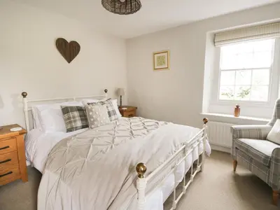 a white bedroom with a white bed and a chair at Beckside Cottage in Welton