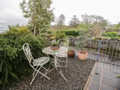 a table and chairs in a garden with plants at Beckside Cottage in Welton