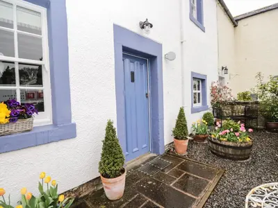 a blue door on a white house with potted plants at Beckside Cottage in Welton