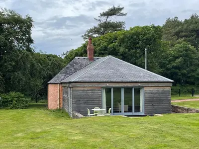 a small house with two chairs in a yard at Ardlochan Lodge - Culzean Castle in Maybole