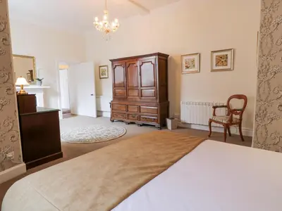 a bedroom with a bed and a cabinet and a chair at Brewhouse Flat - Culzean Castle in Maybole
