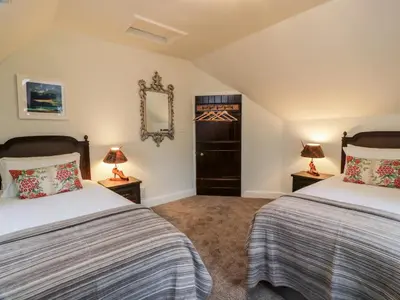 two beds in a room with two lamps at Gate Lodge - Threave Estate in Castle Douglas