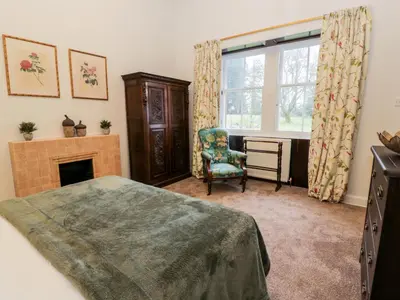 a bedroom with a bed and a chair and a fireplace at Gate Lodge - Threave Estate in Castle Douglas