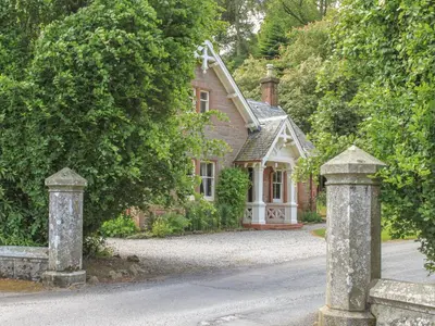 an old house with two stone pillars in front of it at Gate Lodge - Threave Estate in Castle Douglas