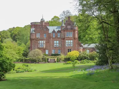 an old red brick building with a garden in front of it at Gate Lodge - Threave Estate in Castle Douglas