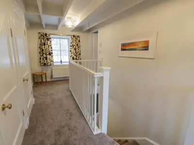 a hallway with a white staircase with a window at Blue Door - Kirkcudbright in Kirkcudbright