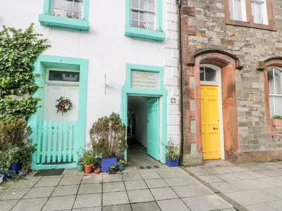 a white building with blue and yellow doors at Blue Door - Kirkcudbright in Kirkcudbright