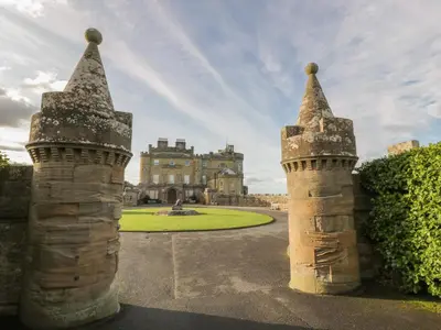 a castle with two towers in front of a building at Royal Artillery Cottage - Culzean Castle in Maybole