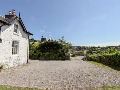 an old stone house with a gravel driveway at Port Donnel Cottage in Dalbeattie