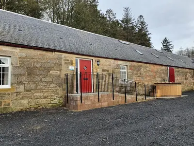 an old stone building with a red door at 2-Bed Barn Hot Tub & Pet Friendly near Muirkirk in Cumnock