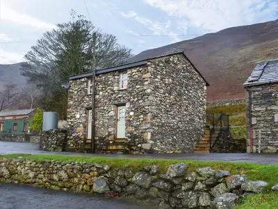 an old stone house with a stone wall at Danika East in Threlkeld