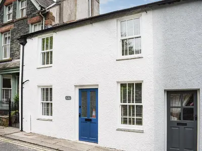 a white house with blue doors on a street at The Plosh in Keswick