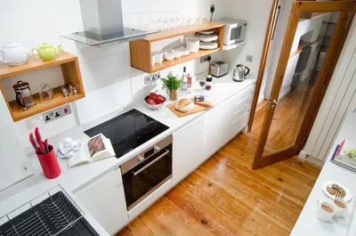 a kitchen with white walls and wooden floors at The Stable At Oakbank in Elterwater