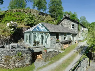 an old stone house with a greenhouse on it at The Stable At Oakbank in Elterwater
