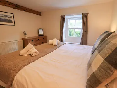 a bedroom with a large bed with towels on it at Yew Tree Cottage Borrowdale in Rosthwaite