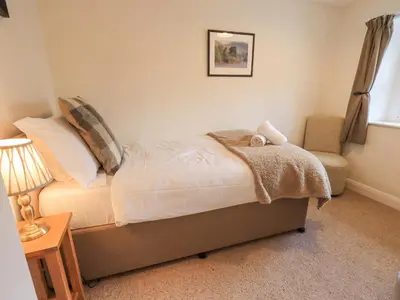 a bedroom with a bed and a lamp and a chair at Yew Tree Cottage Borrowdale in Rosthwaite