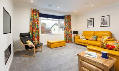 a living room with a yellow couch and a chair at Fell View in Keswick