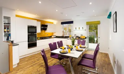 a kitchen and dining room with a table and purple chairs at Fell View in Keswick