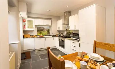 a kitchen with white cabinets and a wooden table at Oxen Fell Cottage in Little Langdale