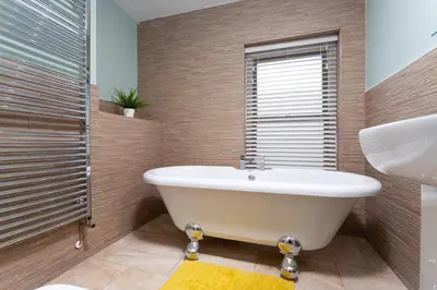 a bathroom with a tub and a shower and a sink at Dovedale in Keswick