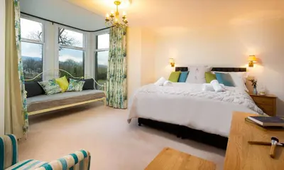 a bedroom with a large white bed and a window at One The Howe in Portinscale