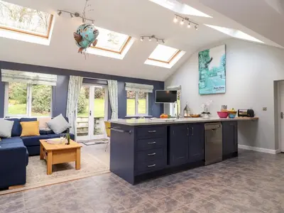 an open kitchen and living room with a blue couch at Merlestead in Applethwaite