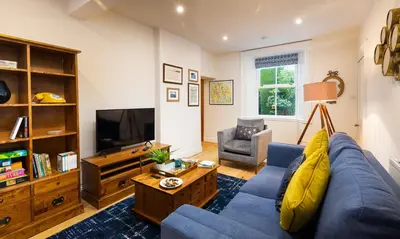 a living room with a blue couch and a tv at Crow Cottage in Keswick