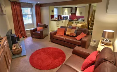 a living room with couches and a red rug at Townfoot Cottage in Elterwater