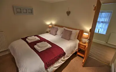 a bedroom with a large bed with towels on it at Townfoot Cottage in Elterwater