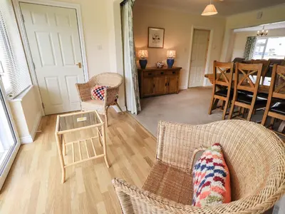 a living room with wicker chairs and a table at Laal Field House in Keswick