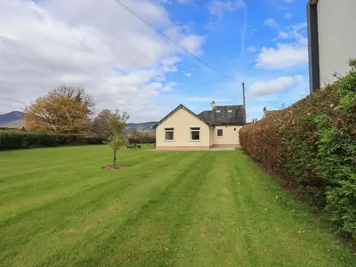 a house in a field with a tree in the yard at Laal Field House in Keswick
