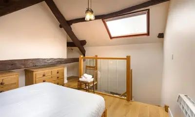 a bedroom with a bed and a window and a mirror at Barn Cottage in Cockermouth