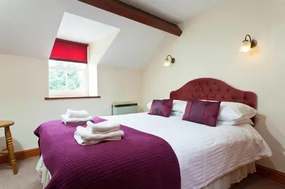 a bedroom with a large bed with purple sheets at Low Croft Cottage in Grasmere