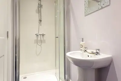 a white bathroom with a sink and a shower at Lake Road Apartment Keswick in Keswick