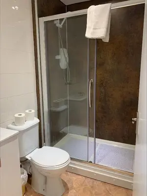 a bathroom with a toilet and a glass shower at Arrandale Apartments in Douglas