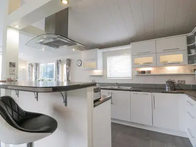 a kitchen with white cabinets and a black counter top at Oyster Bay Lodge in Dalbeattie