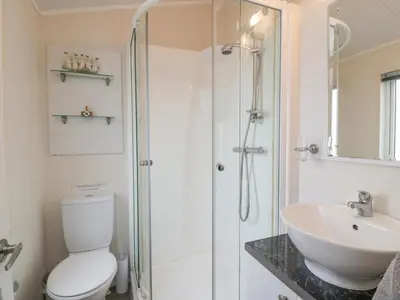 a bathroom with a shower and a toilet and a sink at Oyster Bay Lodge in Dalbeattie