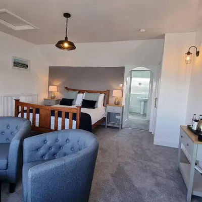 a bedroom with a bed and a couch and a chair at The Steam Packet Inn in Isle of Whithorn