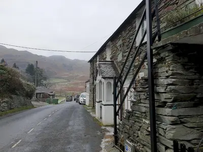 a stone building on the side of a road at Bottom Shop, Elterwater in Chapel Stile