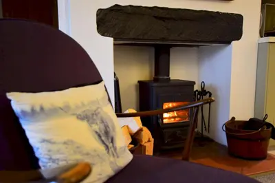 a fireplace in a living room with a stove at Bottom Shop, Elterwater in Chapel Stile