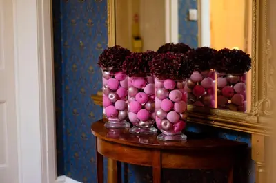 a table with pink vases filled with flowers in front of a mirror at The Gretna Chase Hotel in Gretna