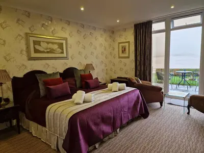 a bedroom with a large bed and a large window at Balcary Bay Country House Hotel in Auchencairn