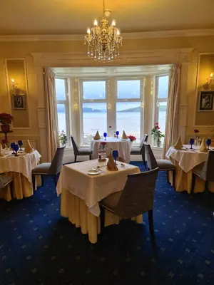 a dining room with tables and chairs and a chandelier at Balcary Bay Country House Hotel in Auchencairn